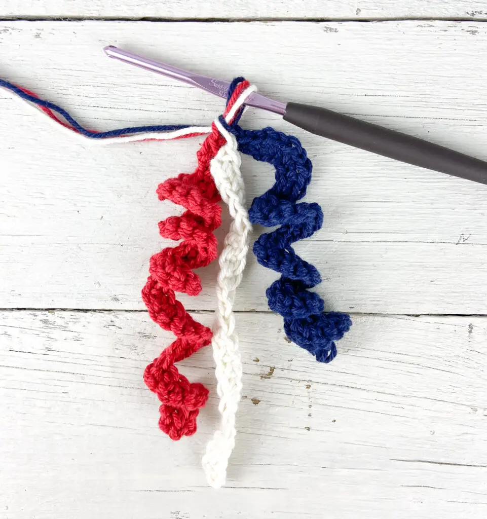 Yarn over with the red, white, and blue tails and pull through