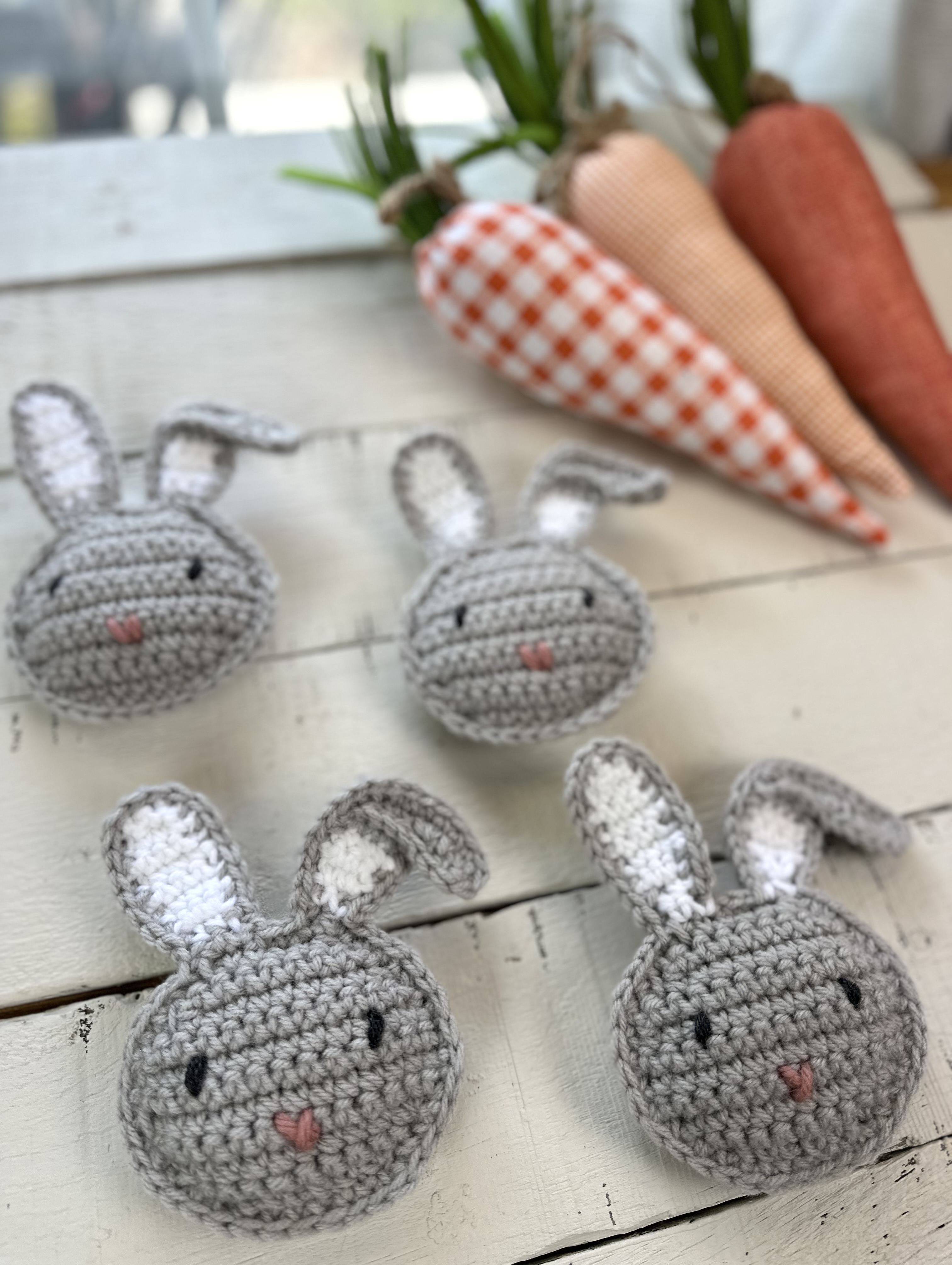 crochet easter bunnies on a table with orange decorative carrots