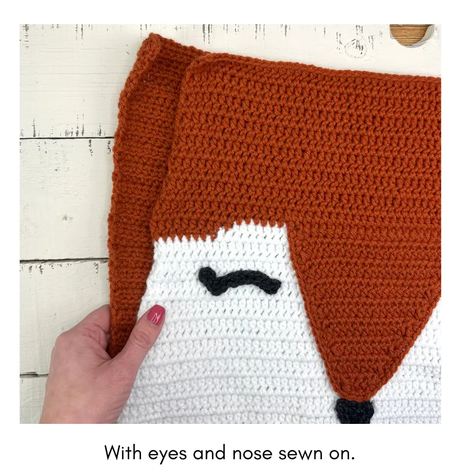 the two panels of the crochet fox pillow with the eyes and nose attached.